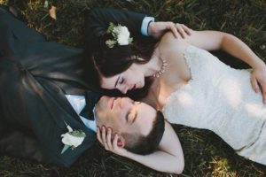 bride and groom laying in grass together
